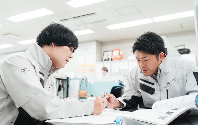 図面を見ながら打ち合わせるスタッフ